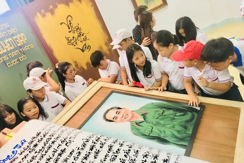Các em học sinh hào hứng tham quan quyển sách thư pháp viết về Đại tướng Võ Nguyên Giáp. (Ảnh: Võ Dung/TTXVN)