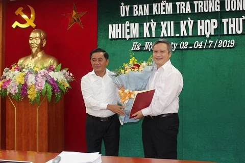 Ông Trần Cẩm Tú trao Quyết định và tặng hoa chúc mừng ông Trần Tiến Hưng. (Nguồn: Ủy ban Kiểm tra Trung ương)