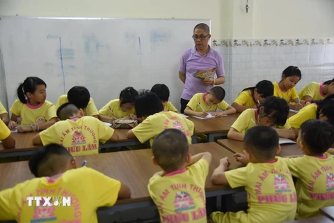 Anh Nguyễn Văn Lâm dạy trẻ học bài ngay tại mái ấm Phúc Lâm. (Ảnh: Công Phong/TTXVN)