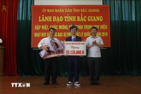 Phó Chủ tịch Lê Ánh Dương trao Bằng khen của Chủ tịch Ủy ban Nhân dân tỉnh và phần thưởng hơn 40,2 triệu đồng cho em Trịnh Duy Hiếu. (Ảnh: Tùng Lâm/TTXVN)