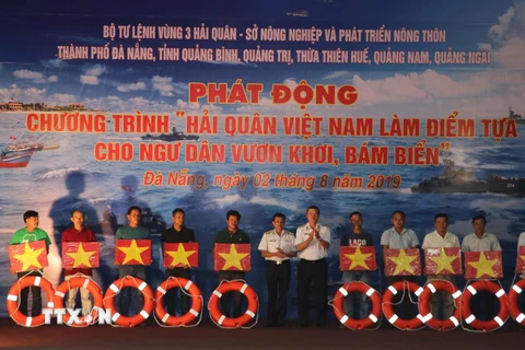 Lãnh đạo Quân chủng Hải quân và Bộ Tư lệnh Vùng 3 Hải quân tặng cờ Tổ quốc, phao cứu sinh cho ngư dân tại chương trình. (Ảnh: Nguyễn Sơn/TTXVN)