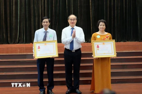 Bí thư Thành ủy Thành phố Hồ Chí Minh Nguyễn Thiện Nhân chúc mừng 2 tập thể có thành tích xuất sắc trong công tác giáo dục và đào tạo được nhận Huân chương Lao động hạng Ba. (Ảnh: Thu Hoài/TTXVN)
