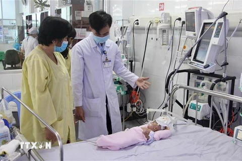 Bác sỹ Dương Thanh Tùng, Khoa Hồi sức tích cực (Bệnh viện Sản-Nhi tỉnh An Giang) thăm khám cho bệnh nhi. (Ảnh: Thanh Sang/TTXVN)