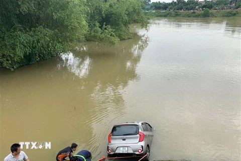 Lực lượng cứu hộ đang tìm cách kéo chiếc xe taxi lên bờ. (Ảnh: Hoa Mai/TTXVN)