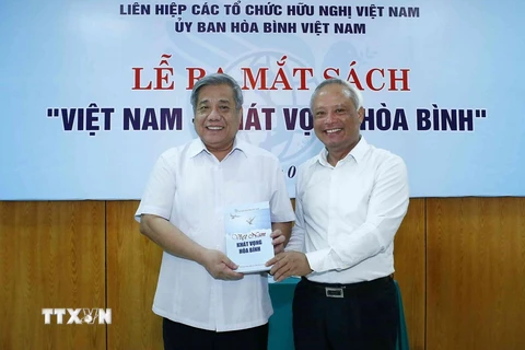 Ông Uông Chu Lưu, Ủy viên Trung ương Đảng, Phó Chủ tịch Quốc hội, Chủ tịch Ủy ban Hòa bình Việt Nam tặng sách cho các đại biểu. (Ảnh: Văn Điệp/TTXVN)