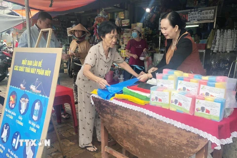 Chị Phan Thị Thúy Phượng (phải) tư vấn cho người tiêu dùng về túi nylon tự hủy sinh học tại chợ Gò Vấp. (Ảnh: Mỹ Phương/TTXVN)