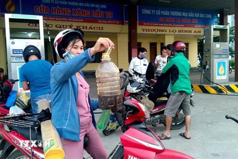 Can xăng mua ở Cửa hàng xăng dầu số 79, đóng trên địa bàn xã Võ Ninh, huyện Quảng Ninh chuyển sang màu vàng đen, có nhiều cặn ở đáy can. (Ảnh: Văn Tý/TTXVN)