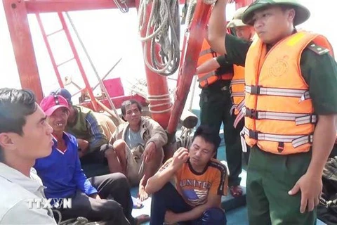Cán bộ, chiến sỹ biên phòng Quảng Bình trò chuyện, thăm hỏi tình hình các thuyền viên tàu bị nạn. (Ảnh: Châu Thành/TTXVN)