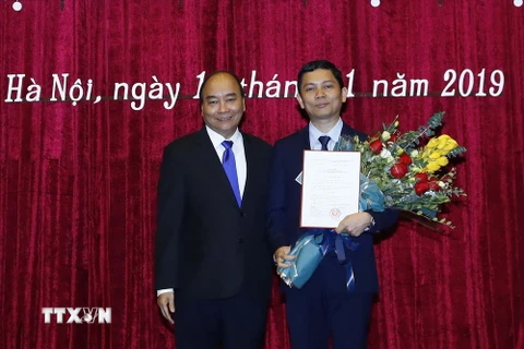 Thủ tướng Nguyễn Xuân Phúc chúc mừng phó giáo sư-tiến sỹ Bùi Nhật Quang. (Ảnh: Thống Nhất/TTXVN)