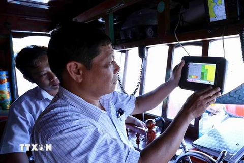 Cán bộ ngành thủy sản kiểm tra thiết bị giám sát hành trình khai thác trên tàu cá trước khi ra khơi, tại cảng cá Quy Nhơn, thành phố Quy Nhơn. (Ảnh: TTXVN)