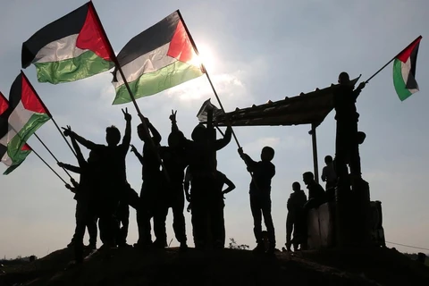Người dân Palestine giơ quốc kỳ tại khu vực biên giới Israel-Gaza. (Nguồn: AFP)