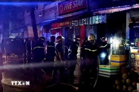 Cảnh sát phòng cháy chữa cháy phá cửa để cứu hộ. (Ảnh: TTXVN)