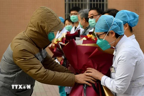 Một bệnh nhân (trái) tri ân các nhân viên y tế sau khi được chữa khỏi bệnh viêm đường hô hấp cấp do nhiễm virus corona chủng mới tại một bệnh viện ở Thiểm Tây, Trung Quốc ngày 4/2/2020. (Ảnh: THX/TTXVN)