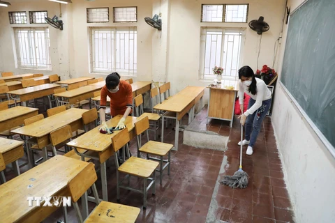 Giáo viên Trường THPT Trương Định, Hà Nội tiến hành vệ sinh, khử khuẩn lớp học lần 2 trong ngày 8/2. (Ảnh: Thanh Tùng/TTXVN)