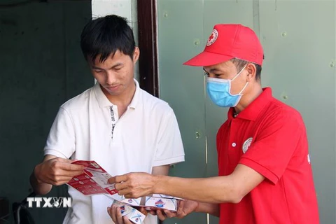 Hội viên Hội Chữ thập Đỏ thành phố Đà Nẵng đến tận nhà dân phát tờ rơi tuyên truyền và xà phòng miễn phí. (Ảnh: Văn Dũng/TTXVN)