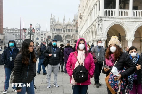 Khách du lịch đeo khẩu trang phòng dịch viêm đường hô hấp cấp COVID-19 tại Venice, Italy ngày 25/2/2020. (Ảnh: AFP/TTXVN)