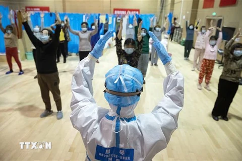 Nhân viên y tế hướng dẫn bệnh nhân nhiễm COVID-19 đang dần hồi phục tập thể dục tại bệnh viện ở Vũ Hán, tỉnh Hồ Bắc, Trung Quốc, ngày 25/2/2020. (Ảnh: THX/TTXVN)
