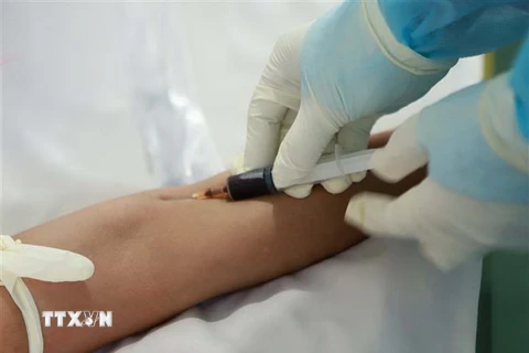 Kỹ thuật viên lấy mẫu máu bệnh nhân làm xét nghiệm. (Ảnh: Hoàng Hùng/TTXVN)