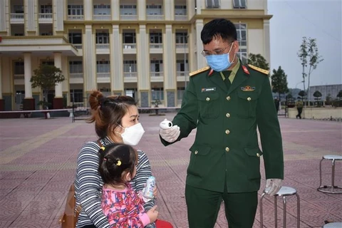 Kiểm tra thân nhiệt công dân tại Trung tâm Giáo dục quốc phòng Trường Quân sự Bộ Tư lệnh Thủ đô Hà Nội. (Ảnh: Nguyễn Cúc/TTXVN)