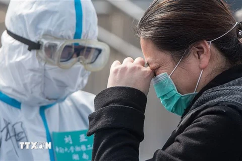 Bệnh nhân nhiễm COVID-19 tạm biệt bác sỹ sau khi được chữa khỏi tại bệnh viện ở Vũ Hán, tỉnh Hồ Bắc, Trung Quốc, ngày 10/3/2020. (Ảnh: THX/TTXVN)