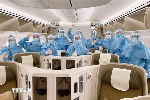 Các phi công, tiếp viên mặc trang phục bảo hộ trước khi thực hiện chuyến bay, cùng găng tay, khẩu trang, kính mắt, khăn tẩm cồn và dung dịch sát khuẩn. (Ảnh: TTXVN)