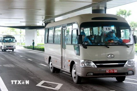 Hành khách xuống sân bay Vân Đồn được lên ôtô chở về khu cách lý theo quy định. (Ảnh: TTXVN)