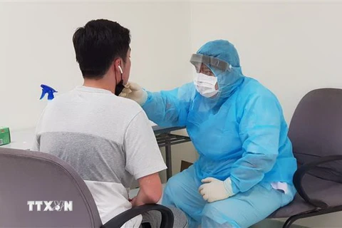Nhân viên y tế của Trung tâm Kiểm dịch y tế quốc tế kiểm tra sức khỏe của hành khách nhập cảnh tại sân bay Tân Sơn Nhất Thành phố Hồ Chí Minh. (Ảnh: TTXVN)