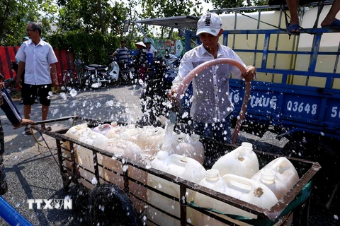 Người dân trên địa bàn xã Thanh Hòa, thị xã Cai Lậy (Tiền Giang) lấy nước ngọt miễn phí tại điểm cung cấp nước ngọt cầu Ông Thiệm. (Ảnh: TTXVN)