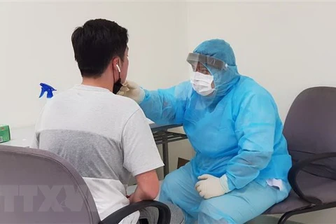 Nhân viên y tế của Trung tâm Kiểm dịch y tế quốc tế kiểm tra sức khỏe của hành khách nhập cảnh tại sân bay Tân Sơn Nhất Thành phố Hồ Chí Minh. (Ảnh: TTXVN)