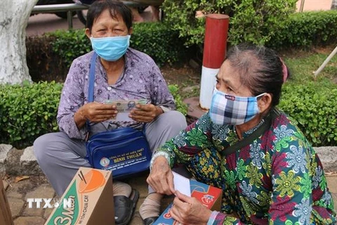 Người bán vé số dạo ở Bình Dương vui mừng nhận quà hỗ trợ. (Ảnh: Nguyễn Văn Việt/TTXVN)