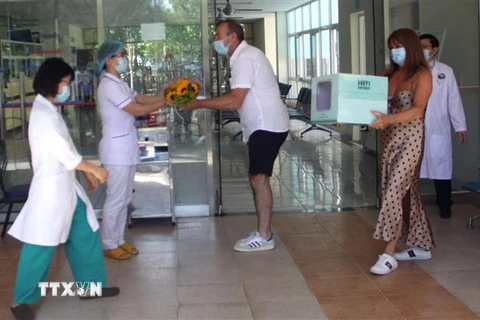 Hai vợ chồng bệnh nhân thứ 57 tặng hoa và quà cho đội ngũ y, bác sỹ Bệnh viện đa khoa Trung ương Quảng Nam. (Ảnh: Trịnh Bang Nhiệm/TTXVN)
