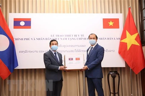 Thứ trưởng Ngoại giao Nguyễn Quốc Dũng (bên phải) trao biểu trưng thiết bị y tế cho Đại sứ Lào tại Việt Nam Sengphet Houngboungnuang. (Ảnh: Dương Giang/TTXVN)