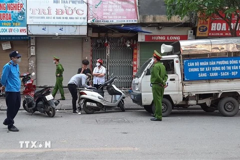 Tổ công tác phường Đồng Nhân (quận Hai Bà Trưng, Hà Nội) xử phạt các trường hợp vi phạm không đeo khẩu trang ra đường. (Ảnh: Doãn Tấn/TTXVN)