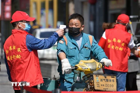 Tình nguyện viên kiểm tra thân nhiệt của người dân tại Vũ Hán, tỉnh Hồ Bắc, Trung Quốc ngày 15/4/2020. (Ảnh: THX/TTXVN)