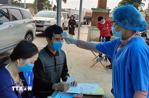 Cán bộ y tế tiến hành đo thân nhiệt và kê khai y tế tại chốt kiểm soát COVID-19 cầu Vàng Chua, thị xã Đông Triều, tỉnh Quảng Ninh. (Ảnh: Đức Hiếu/TTXVN)
