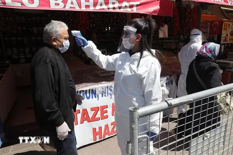 Nhân viên y tế kiểm tra thân nhiệt người dân tại một khu chợ ở Ankara, Thổ Nhĩ Kỳ nhằm ngăn chặn sự lây lan của dịch COVID-19 ngày 17/4/2020. (Ảnh: THX/TTXVN)