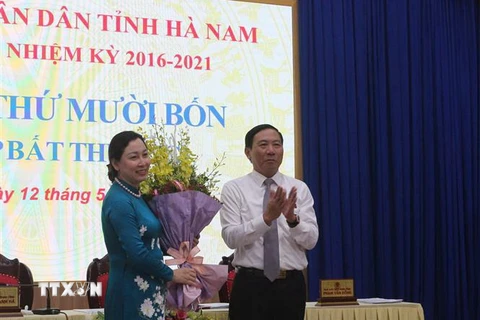 Ông Phạm Sỹ Lợi, Chủ tịch HĐND tỉnh Hà Nam tặng hoa chúc mừng bà Đinh Thị Lụa. (Ảnh: Thanh Tuấn/TTXVN)