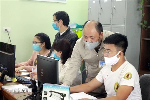 Cán bộ Chi cục Thuế ở Bắc Giang hướng dẫn nhân viên một công ty làm thủ tục gia hạn nộp thuế. (Ảnh: Đồng Thúy/TTXVN)