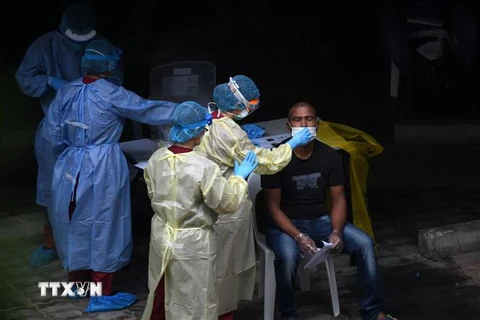 Nhân viên y tế lấy mẫu xét nghiệm COVID-19 cho người lao động nước ngoài tại khu ký túc xá ở Singapore. (Ảnh: AFP/TTXVN)