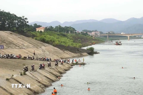 Người dân dựng xe la liệt bên bờ sông Đà để xuống tắm sông, phớt lờ cảnh báo nguy hiểm. (Ảnh: Trọng Đạt/TTXVN)