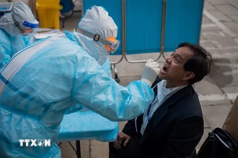Nhân viên y tế lấy mẫu xét nghiệm COVID-19 cho người dân tại Bắc Kinh, Trung Quốc. (Ảnh: AFP/TTXVN)