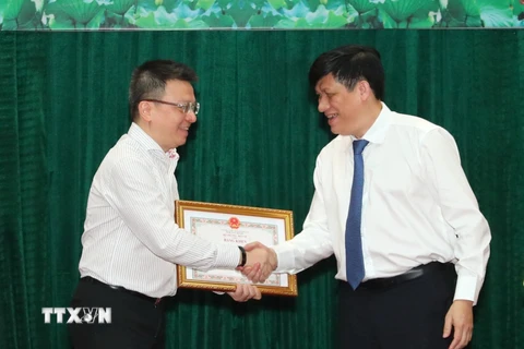 Thứ trưởng Bộ Y tế Nguyễn Thanh Long trao Bằng khen cho nhà báo Lê Quốc Minh, Phó Tổng Giám đốc TTXVN vì thành tích xuất sắc trong công tác thông tin, tuyên truyền về phòng, chống dịch COVID-19. (Ảnh: Thành Đạt/TTXVN)
