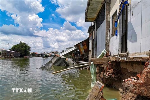 Vụ sạt lở làm phần nhà sau của 13 hộ dân sống ven sông Trà Nóc bị sụp hoàn toàn xuống sông. (Ảnh: Thanh Liêm/TTXVN)