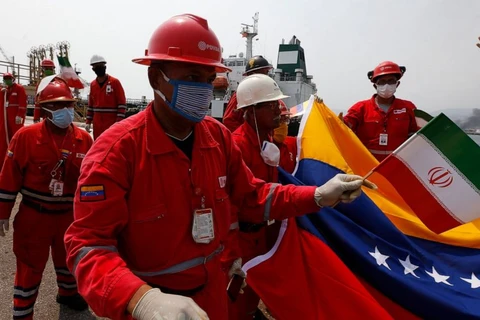 Một công nhân dầu mỏ Venezuela cầm lá cờ Iran chào đón tàu chở dầu Fortune hồi tháng 5/2020. (Nguồn: AP)
