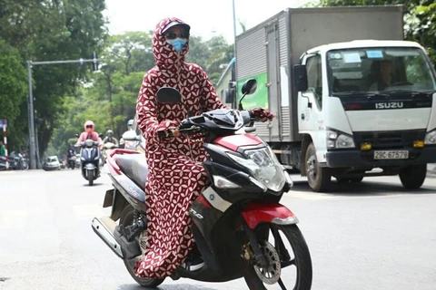 Người dân mặc trang phục kín mít để chống chọi lại thời tiết nắng gắt khi tham gia giao thông. (Ảnh: Danh Lam/TTXVN)