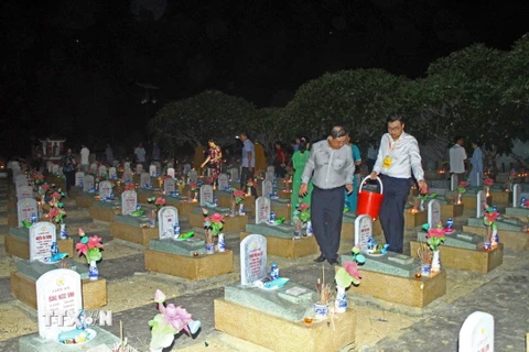 Nghi lễ rải đậu cát tường cầu siêu tại các phần mộ anh hùng, liệt sỹ yên nghỉ ở Nghĩa trang Liệt sỹ Quốc tế Việt-Lào. (Ảnh: Tá Chuyên/TTXVN)