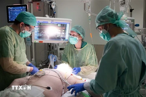 Nhân viên y tế điều trị cho bệnh nhân mắc COVID-19. (Ảnh: AFP/TTXVN)