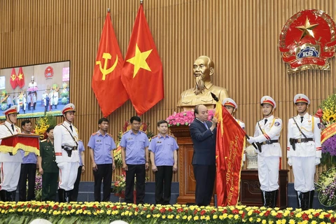 Thủ tướng Nguyễn Xuân Phúc gắn Huân chương Hồ Chí Minh lên lá cờ truyền thống của Viện Kiểm sát Nhân dân Tối cao. (Ảnh: Doãn Tấn/TTXVN)