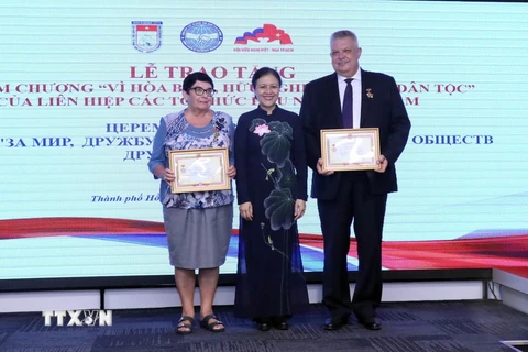 Bà Nguyễn Phương Nga trao tặng Kỷ niệm chương cho ông Aleksei Vladimirovich Popov và bà Natalia Borisovna Zolkina. (Ảnh: Xuân Khu/TTXVN)