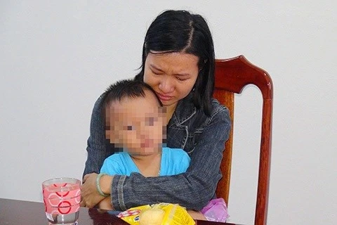 Nguyễn Thị Tuyết Trinh ôm con đến công an đầu thú. (Nguồn: Cơ quan công an)